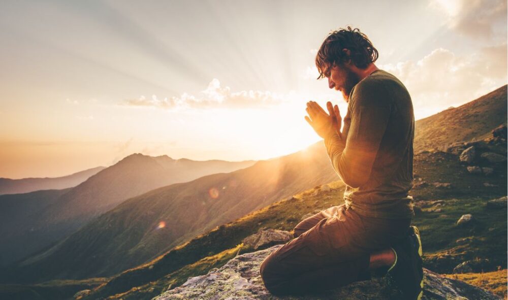 Homem ajoelhado em oração na montanha