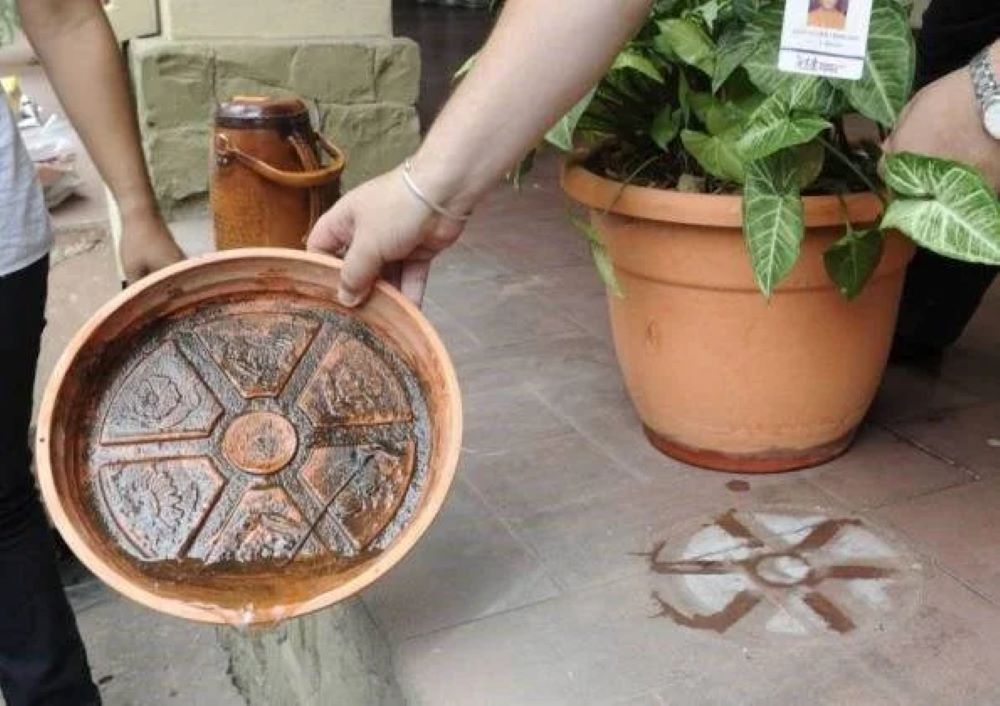 Mão virando prato do vaso de planta para retirar água parada